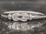 a silver ring with a knot on it on a table