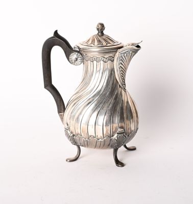 une cafetière ancienne en argent posée sur un support, sur fond blanc