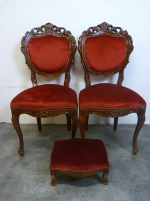trois chaises rouges et un repose-pieds devant un mur blanc