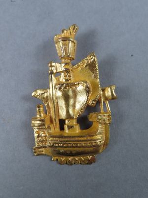 une image représentant une broche en or sur laquelle figure un navire surmonté d'une couronne