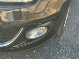 un gros plan sur le phare d'une voiture avec le reflet d'un immeuble en arrière-plan