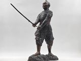 a statue of a man holding a sword on a rock