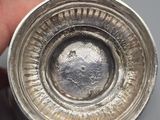 someone is holding a silver object in their hand on a table