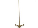 a brass floor lamp with a beige shade on a white background