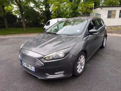 La voiture grise est garée sur le parking à côté de la maison.