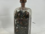a glass bottle with a small amount of rocks inside of it
