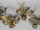 three wall sconces with flowers and leaves on them on a white surface