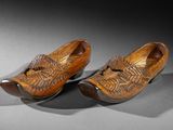 pair of wooden shoes on a gray surface with shadows
