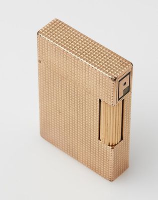a gold lighter sitting on top of a white surface
