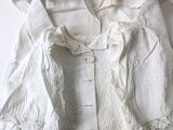a white dress with a lace collar and buttons on it