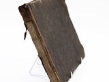 an old book on a stand on a white surface