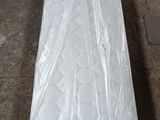 un matelas emballé dans du plastique, posé par terre