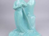 une figurine bleue représentant une femme avec un chapeau et une canne