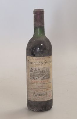 an old bottle of wine sitting on top of a white table