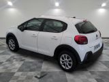 the back end of a white car in a room with a checkered floor