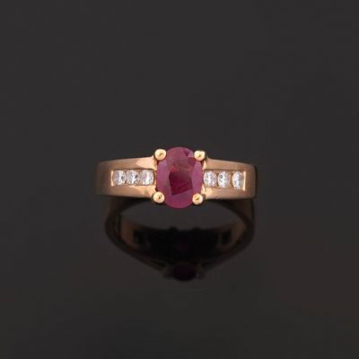 an oval ruby and diamond ring on a black surface
