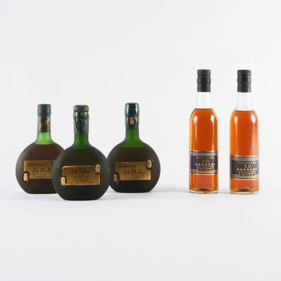 trois bouteilles d'alcool sont alignées sur une surface blanche