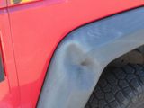 a close up of a red truck with a black tire