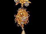 a close up of a gold and pearl broochle on a black background