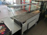 tables and chairs in a restaurant with a counter and a glass case