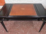une table noire avec un plateau en cuir marron et deux tiroirs