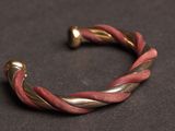 a close up of a red and gold bracelet on a black surface