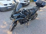 a black motorcycle parked in a parking lot next to a white van