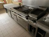 une grande cuisinière en acier inoxydable dans une cuisine dotée de nombreux plans de travail