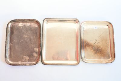 trois petits plateaux en métal posés les uns à côté des autres sur une surface blanche