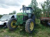 a tractor that is sitting in the grass next to a truck