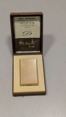 un briquet plaqué or dans un coffret en bois posé sur une table