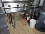 an image of a commercial kitchen with a stove and trash can