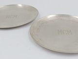 two silver plate with engraved names on them on a white surface