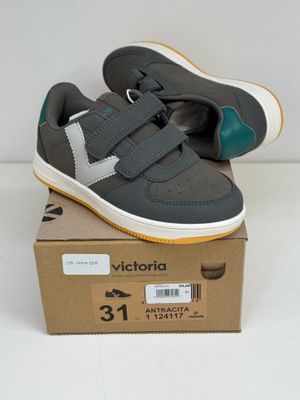 des baskets grises et vertes à velcro, avec des bandes de velcro posées sur une boîte en carton