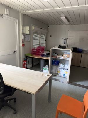 a room with a table, chairs, and a refrigerator in it