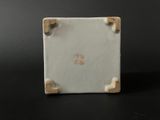 a close up of a small square white ceramic object on a black surface