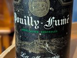 a bottle of wine sitting on top of a wooden barrel