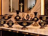 a lot of black and gold vases sitting on a table