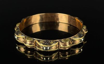 a close up of a gold bracelet on a black surface