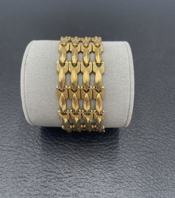 un gros plan d'un bracelet en or posé sur une bague blanche