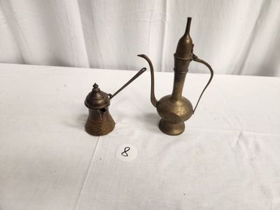 two antique brass teapots on a table with a white table cloth