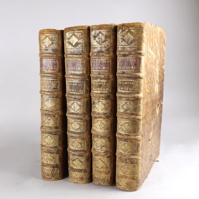 trois vieux livres sont empilés sur une surface blanche
