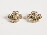 a pair of silver flower earrings on a white surface