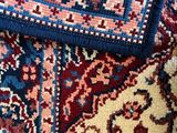 several different colored rugs on a wooden floor with a cat sleeping on top of them
