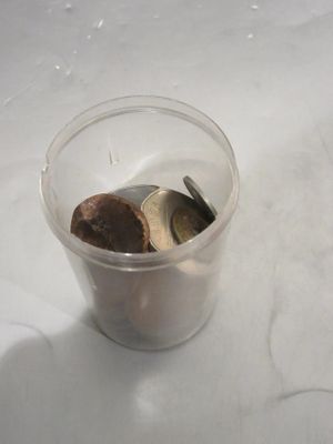 un gobelet en plastique contenant des pièces de monnaie posé sur une table