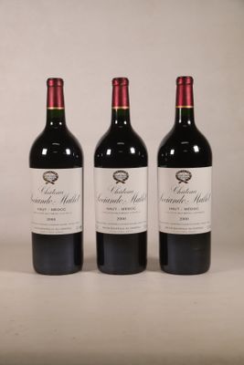 trois bouteilles de vin rouge posées sur une table blanche