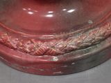 a red vase that has a red apple on top of it