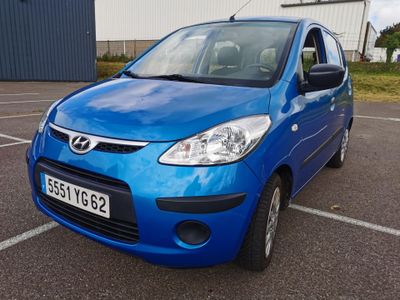 une voiture bleue garée sur un parking devant un immeuble