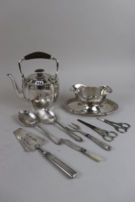 a silver tea set with silverware on a white table