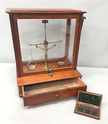 une caisse en bois contenant une balance et une boîte posée par terre